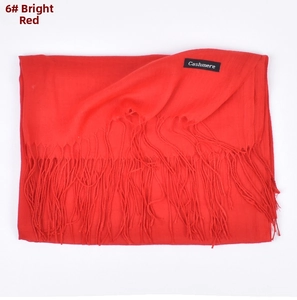 Detail view of red cashmere scarf showing soft texture, fringe edges and garment label