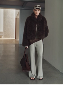 Chic dark brown faux fox fur vest paired with green flare pants and a large leather tote bag