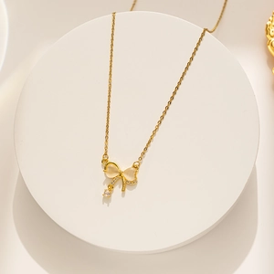 Detailed shot of bow pendant necklace with white cat eye stone and crystal on white stand