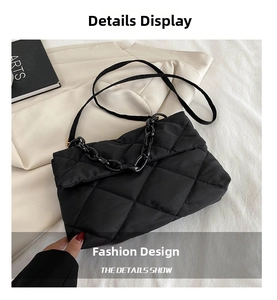 Detail view of black quilted shoulder bag with chain strap on a textured blazer