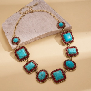 Detail of bohemian gold necklace with turquoise resin stones and red rhinestones