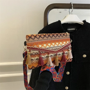 Detail of bohemian woven crossbody bag featuring a tassel charm and colorful geometric strap