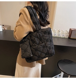 Detail of black quilted tote bag featuring floral embroidery and matching pouch