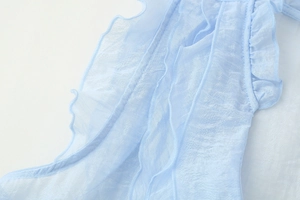 Macro shot of light blue chiffon fabric showing detailed ruffles and pleat textures