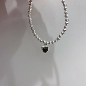 Close-up of vintage black heart pendant on silver bead bracelet with elegant detailing