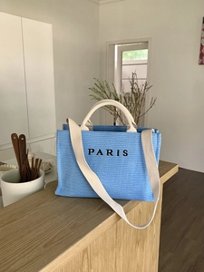 Close-up of blue woven tote bag with Paris print and canvas handles on a bar counter