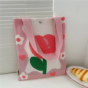 Detail of floral knit tote bag featuring red and white flowers with a top snap closure