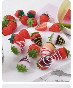 Macro detail of artificial strawberry models with chocolate coating and metal hooks