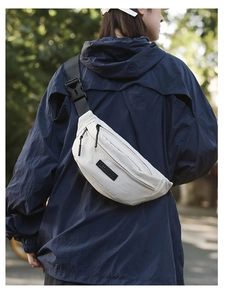 Close-up of white nylon crossbody bag with black adjustable strap worn by model