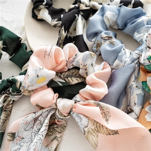 Close-up of assorted floral satin scrunchies in pink, blue and green with silky texture