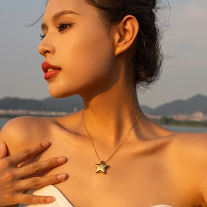 Minimalist 18k gold star pendant necklace worn by a model against a sunset backdrop