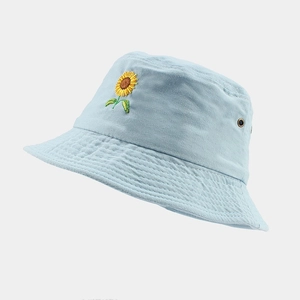 Détail de la broderie tournesol et des oeillets en métal sur un chapeau bob bleu ciel