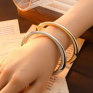 Close-up of minimalist gold and silver plated open bangles in a vintage lifestyle setting