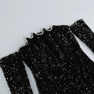 Détail d'une robe noire à paillettes avec bordure en strass argentés et décolleté ondulé