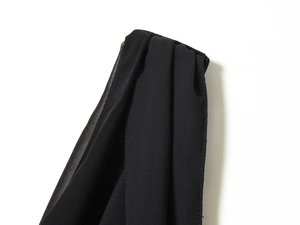 Detailaufnahme des plissierten schwarzen Chiffonstoffs und der feinen Nähte am Kleid