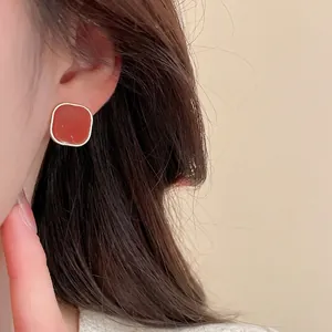 French vintage gold square stud earrings with dark red enamel inlay on model