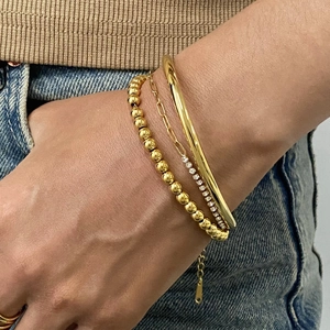 Gros plan d'un ensemble de bracelets dorés avec perles, zircons pavés et jonc poli