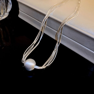 Macro detail of multi-layer silver snake chain with frosted matte bead pendant