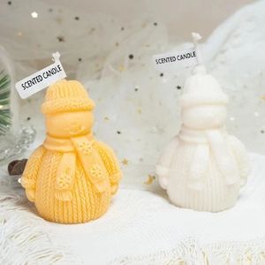 Handmade Christmas snowman scented candles with knitted hats and scarves on white fabric