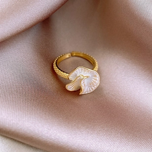 Detailed close-up of a gold-plated butterfly ring on smooth champagne silk fabric