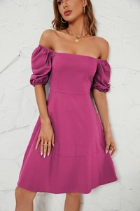 Detail of square neck puff sleeve dress in vibrant magenta on a textured white wall