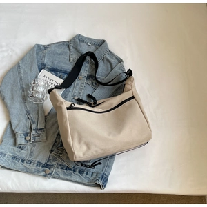 Detail of canvas messenger bag with adjustable strap on a denim jacket background