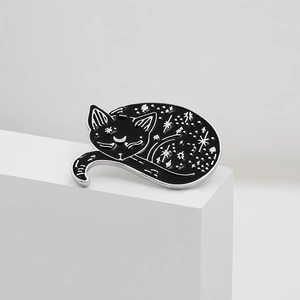 Dettaglio della spilla a forma di gatto nero e argento con motivi di luna e stelle