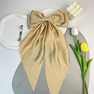 Barrette à cheveux oversize en satin doré champagne avec rubans sur un fond décoratif chic