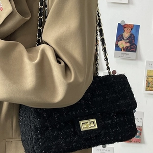 Classic black tweed quilted shoulder bag with gold chain strap shown on model in a studio