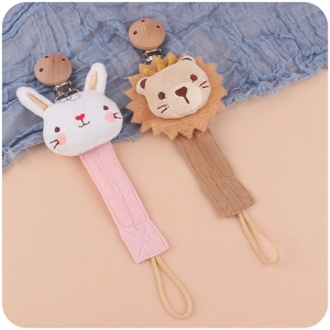 Detail of wooden pacifier clips with plush rabbit and lion on cotton fabric straps