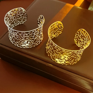 Detailed view of wide irregular hammered gold and silver hollowed-out cuff bracelets