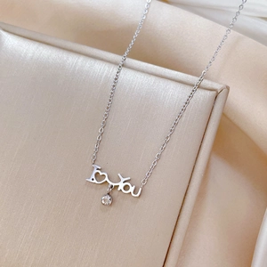 Macro view of silver I Love You pendant with zircon on champagne silk background