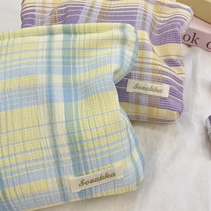 Close-up of checkered seersucker makeup bags with Sozakka label in blue and purple