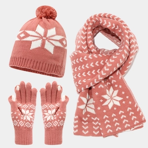 Detail of pink knitted winter set featuring white snowflake patterns and soft pom-poms