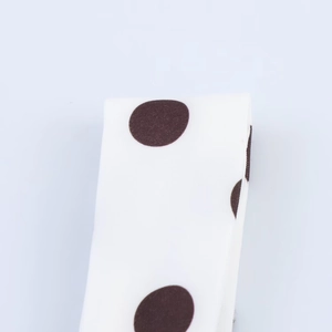 Vue détaillée du tissu blanc à grands pois marrons avec une texture lisse