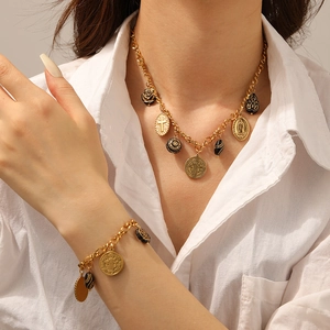 Detail of vintage gold necklace and bracelet set with black resin charms and embossed coins