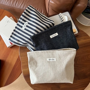 Trio of vintage canvas cosmetic bags with striped and herringbone textures on wooden table