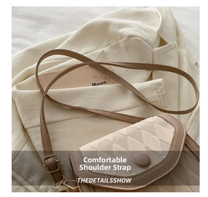 Detail of adjustable leather strap and beige quilted crossbody bag on a textured blazer