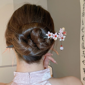 Detail of pink resin cherry blossom hair pin with flowing bead tassels on model