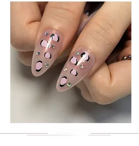 Macro shot of pink leopard print press-on nails with colorful rhinestones detail