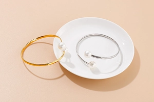 Detailed view of gold and silver open bangle bracelets with elegant white pearls