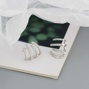 Dettaglio degli orecchini in argento a linee curve con incastonatura di micro zirconi