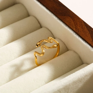 Detail shot of golden snake ring with scales and black enamel eyes on velvet