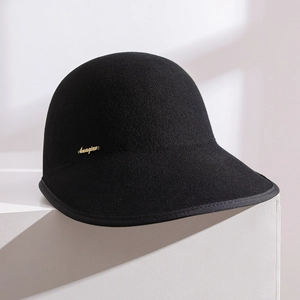 Macro detail of black wool felt texture and gold logo on the wide brim equestrian cap