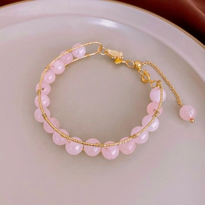 Macro shot of handmade wire-wrapped pink quartz beaded bracelet with gold lobster clasp