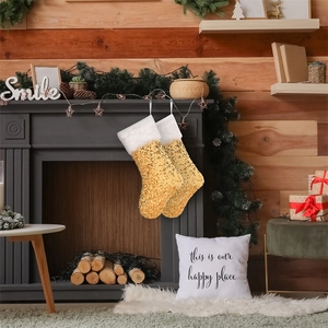 Dettaglio di due calze di Natale con paillettes dorate appese a un camino rustico