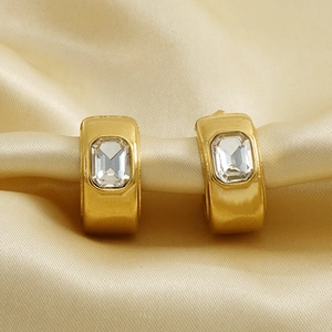 Boucles d'oreilles géométriques en C dorées avec grand zircon sur fond de soie