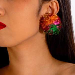 Detailaufnahme von glitzernden Tinsel-Bommel-Ohrringen für Weihnachten am Model
