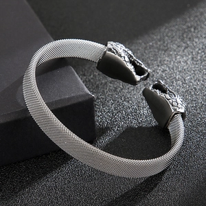 Macro detail of punk-style snake head on a woven stainless steel mesh cuff bracelet