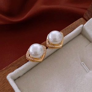 Vue macro d'une boucle d'oreille perle dorée avec strass sur un coffret en bois